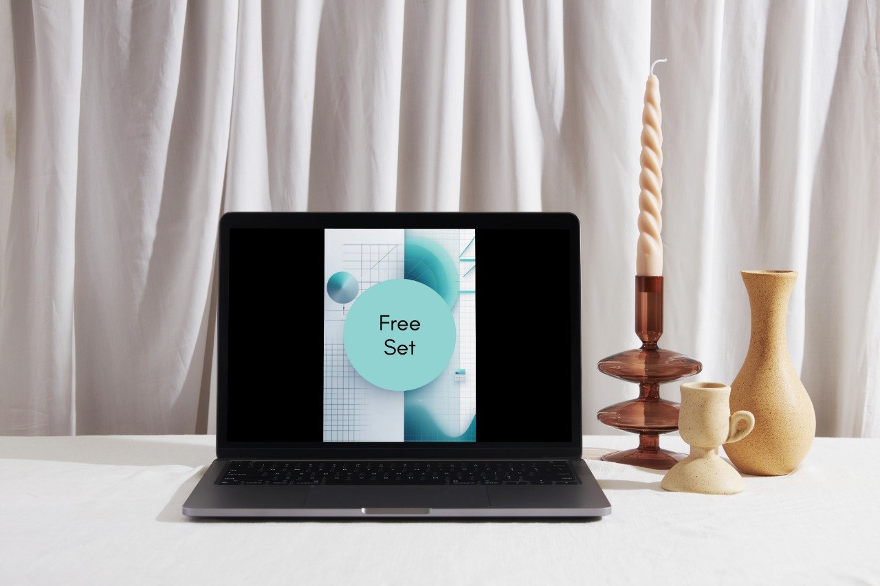 A black laptop displaying a graphic with the text 'Nexus Series' sits on a white tablecloth in front of white draped curtains, styled with a tall spiral candle in a wooden holder, a small ceramic cup, and a beige vase.