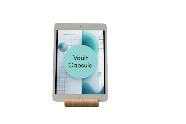 A tablet device displaying a digital cover with the text 'Vault Capsule' on a light blue circle over a geometric teal and white background. The tablet is resting on a small cylindrical wooden stand against a plain white background.